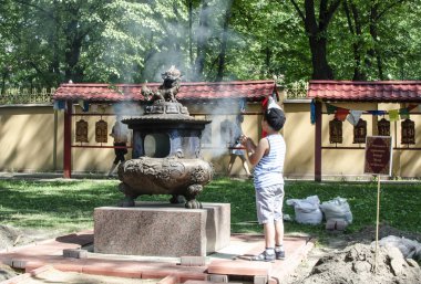 St. Petersburg 'da. Rusya. Haziran 2019: çocuk ritüel kase de dua ediyor. Budist tapınağının avlusunda. Güneşli sıcak gün