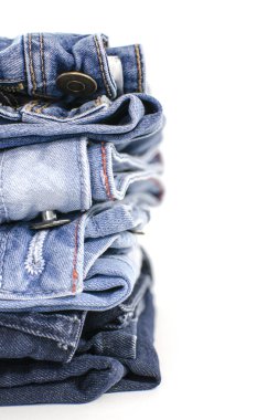 Beyaz arka plan denim mavi kot yığını. Giysi, moda, hayır severlik