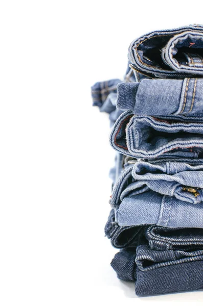 Beyaz arka plan denim mavi kot yığını. Giysi, moda, hayır severlik