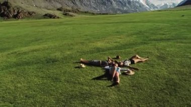 yeşil çim üzerinde yalan ve having fun bir çayır güneşli gün ve dağ arka plan üzerinde üç çekici kızlar