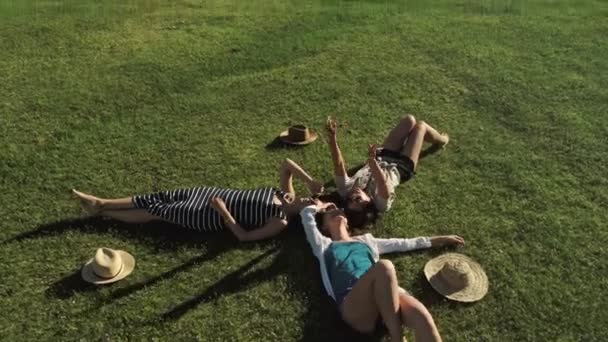 Trendy hipster ragazze rilassarsi sull'erba. Stile di vita estivo ritratto di tre donne hipster sdraiate sull'erba godere di una bella giornata. Migliori amiche ragazze divertirsi, gioia . — Video Stock