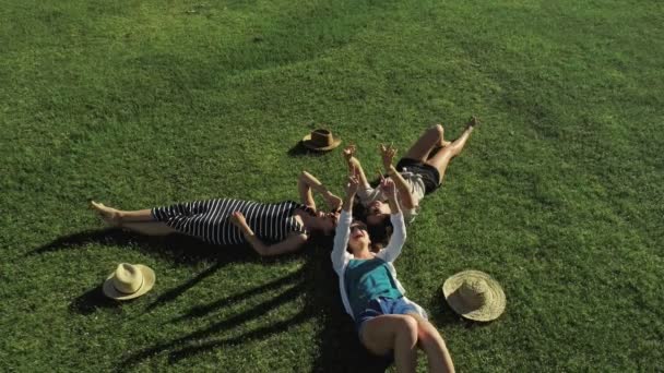 Drie mooie meisjes liggen op gras en plezier op een weide zonnige dag en de achtergrond van de berg — Stockvideo