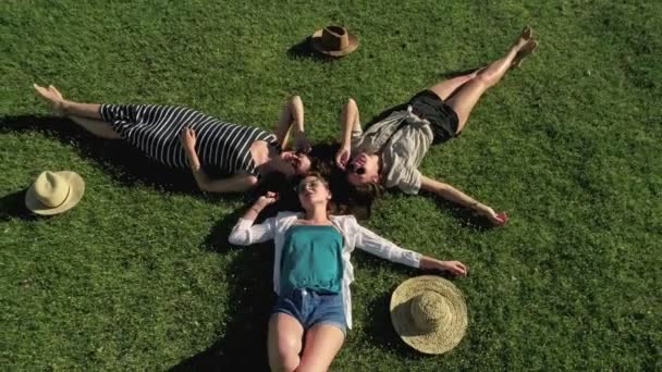 Drie mooie meisjes liggen op gras en plezier op een weide zonnige dag en de achtergrond van de berg — Stockvideo