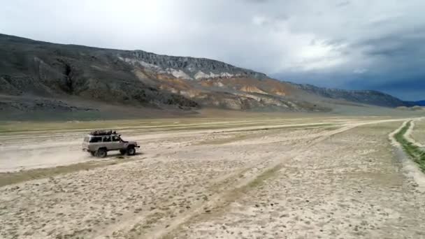 4K vue aérienne du véhicule safari conduisant sur la route de la piste de sable dans la montagne Altay — Video