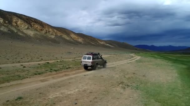 4К вид с воздуха на сафари автомобиль, движущийся по дороге песчаной дорожки в горах Алтай — стоковое видео