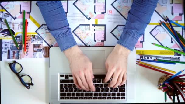 Vista superior da mesa com material de escritório. Homem digitando em seu laptop — Vídeo de Stock