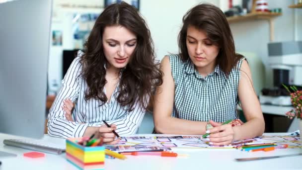 Молодые женщины-архитекторы обсуждают с помощью чертежа в офисе — стоковое видео