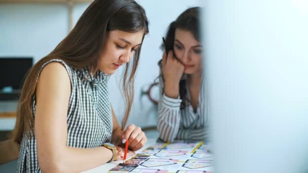 Молодые женщины-архитекторы обсуждают с помощью чертежа в офисе — стоковое видео