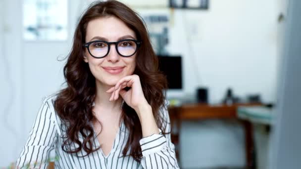 Retrato filmado de mulher atraente olhando para a câmera e sorrindo enquanto trabalhava no escritório urbano. de perto — Vídeo de Stock