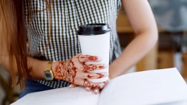 Gros plan d'une femme assise et écrivant dans son journal dans un café animé — Video