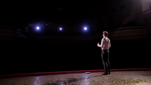 Zadní pohled na podnikatel reproduktor stojící na pódiu ve světlech, osoba říká o marketing a management pro úspěšný prodej středoškolským studentům uvnitř closeup — Stock video