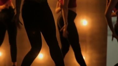 Kızlar dans siluetleri. go-go dansı. Sarı ışık ile karanlık bir sahnede closeup dans performansı oldukça kadın grubu. takım dans topuklu kadınların
