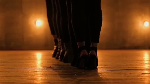 Силуэты танцовщиц. Go-Go танец. Крупный план танцевального представления красивой женской группы на темной сцене с желтыми огнями. командный танец женщин на высоких каблуках. 4k — стоковое видео