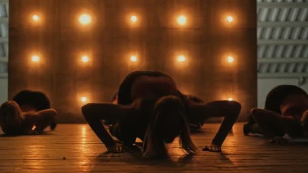 Silhuetas de meninas dançarinas. Dança de go-go. Desempenho de dança close-up de grupo feminino bonito em um palco escuro com luzes amarelas. dança de equipe de mulheres de salto alto — Vídeo de Stock