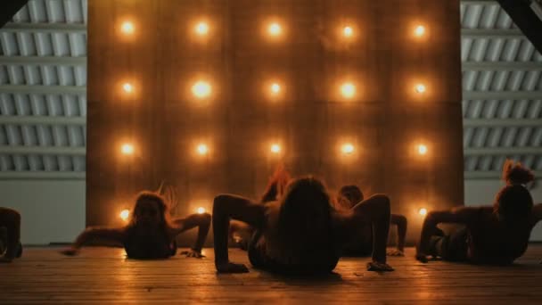 Des silhouettes de danseuses. Va danser. Performance de danse en gros plan d'un joli groupe féminin sur une scène sombre avec des lumières jaunes. danse d'équipe de femmes en talons hauts. 4k — Video