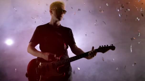 De gitarist voert op het podium. Fase licht, rook. Van bovenaf vallen gouden confetti — Stockvideo