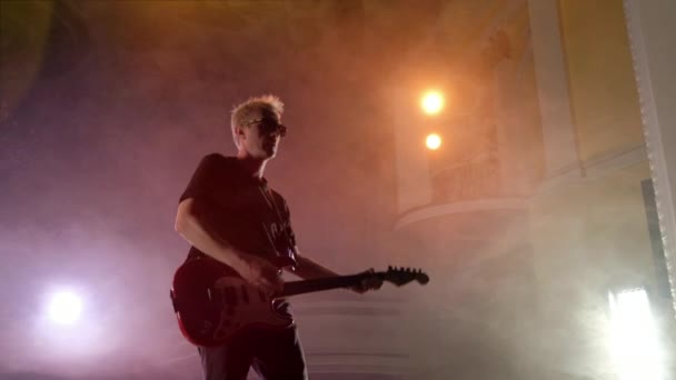 De gitarist voert op het podium. Fase licht, rook. — Stockvideo