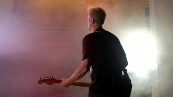 De gitarist voert op het podium. Fase licht, rook. — Stockvideo