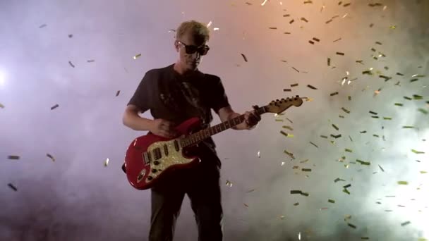 De gitarist voert op het podium. Fase licht, rook. Van bovenaf vallen gouden confetti — Stockvideo