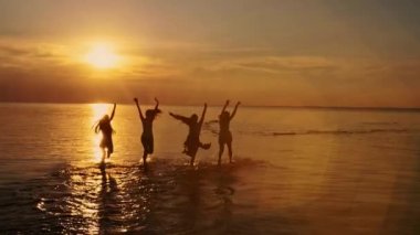 Yaz günbatımı üzerinde püskürtme çalıştıran ve sahilde günbatımı Dancing, suda oynarken mutlu kız grubu. Plaj partisi. Güneş parlaması. Ağır çekim