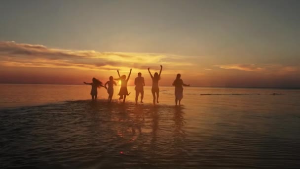 Gran multitud de amigos divirtiéndose en la playa del mar puesta del sol. Concepto de vacaciones de playa. Belleza y alegres amigos adolescentes divirtiéndose, bailando, rociando durante el atardecer de verano. Fiesta en la playa. Bengala solar. Movimiento lento — Vídeos de Stock