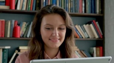 Kütüphanede tablet bilgisayar kullanan sevimli genç bir öğrenci.