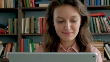 Kütüphanede tablet bilgisayar kullanan sevimli genç bir öğrenci.