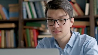 Sınav hazırlayan ve okul kütüphanesinde öğrenim dersleri alan öğrenci, dizüstü bilgisayarda araştırma yapıyor ve internette geziniyor