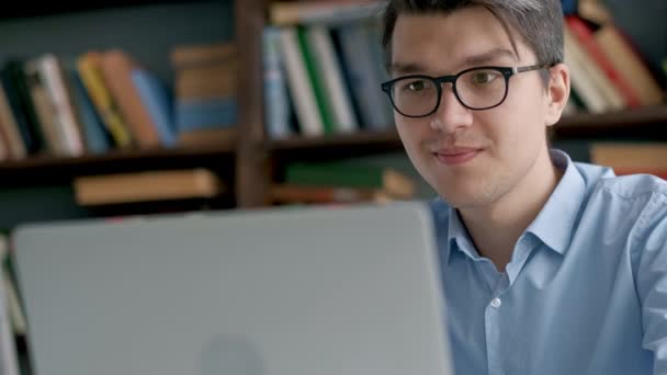 Student připravuje zkoušky a výuku ve školní knihovně, provádí výzkum notebooku a prohlíží si internet — Stock video