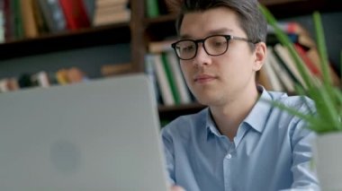 Dizüstü bilgisayar ekranında düşünceli ödev yaparken arayan erkek üniversite öğrenci. Portre konsantre çocuğun eğitimine devam ederken zor görevi yerine getirmek çalışıyor