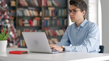 Sınav hazırlayan ve okul kütüphanesinde öğrenim dersleri alan öğrenci, dizüstü bilgisayarda araştırma yapıyor ve internette geziniyor