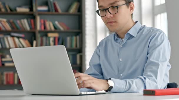 Mannelijke universiteitsstudent kijken laptop scherm zorgvuldig terwijl het doen van huiswerk. Close-up van geconcentreerde jongen probeert te vervullen van de moeilijke taak tijdens de studie. — Stockvideo