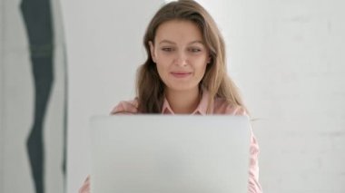 Gülümseyen öğrenci Kitaplığı içinde laptop üzerinde çalışıyor