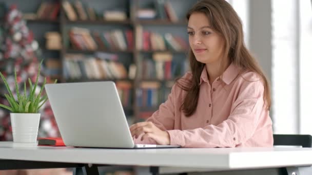 Mulher empresária trabalhando no laptop em co-trabalho escritório ou biblioteca, parece inteligente, estantes. Conhecimento e autodesenvolvimento . — Vídeo de Stock