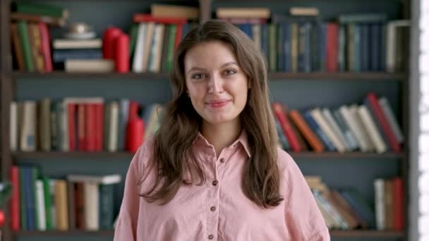 Porträt junge Studentin lächelnd Bücherregal Bibliothek Universität — Stockvideo