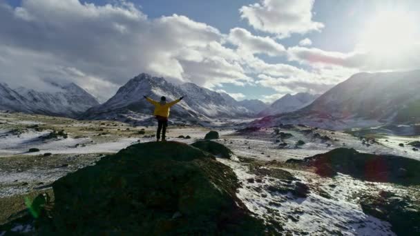 Man Standing On Rock Peak Snowy Winter Mountain Range Achievement Success Outstretched Arms Happiness Epic Nature Beauty Vacation Ski Holiday Concept — Stock Video