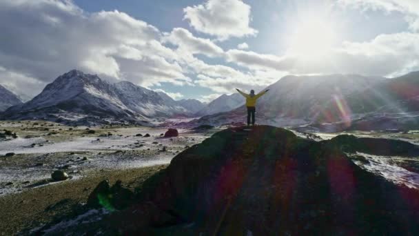 Eenzame bergbeklimmer worden verpozing op besneeuwde berg hoog boven de wolken in de zon, bergbeklimmer bereikt de top van een besneeuwde berg in een zonnige winterdag. — Stockvideo