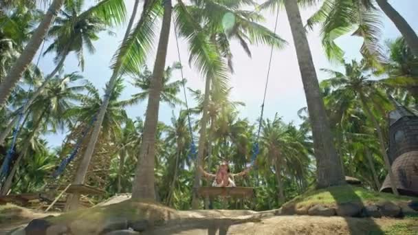 Egy lány a swing hinták, és nézi a naplementét, trópusi tengerparton. Szabadság, pihenés, nyaralás, utazási koncepció — Stock videók
