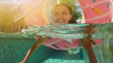 Kadın mavi bikini şişme pembe çörek float havuzu içinde güneşli yaz günü yatan güneş gözlüklü. Kameraya bak. Kadın bikini yüzme havuzunda rahatlatıcı tatil karpuz Kauçuk halka