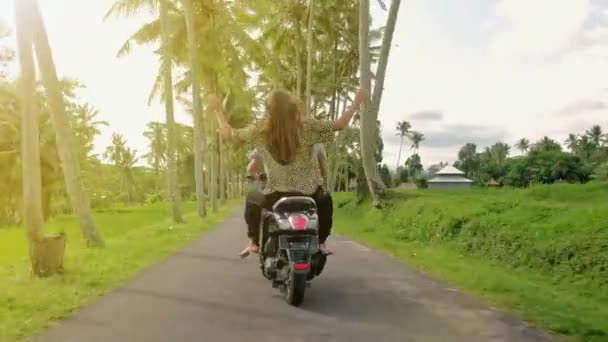 Happy couple tripping by motorcycle on tropical road at sunset time. Outdoor shot of young couple riding motorbike. Man riding on a motorcycle with girlfriend on rural road. — Stock Video