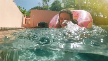 Kadın mavi bikini şişme pembe çörek float havuzu içinde güneşli yaz günü yatan güneş gözlüklü. Kameraya bak. Kadın bikini yüzme havuzunda rahatlatıcı tatil karpuz Kauçuk halka