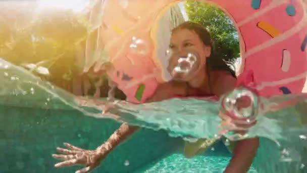 Jonge hipster duizendjarige meisje in bestrooid donut float bij zwembad, glimlachend camera kijken. Gelukkig jongedame ontspannen op opblaasbaar zwembad speelgoed in blauwe zwembad op een zonnige dag. — Stockvideo