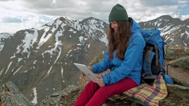 Lány természetjáró egy tabletta ült egy sziklán, a háttér, hegyek és tavak, Norvégia — Stock videók