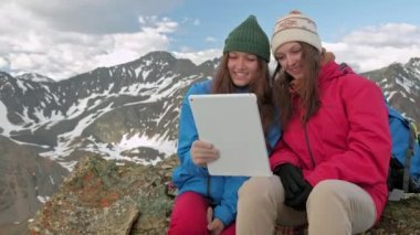 Dağlar ve göller, Norveç bir arka plan üzerinde bir kayanın üzerine oturmuş bir tablet ile kızlar uzun yürüyüşe çıkan kimse