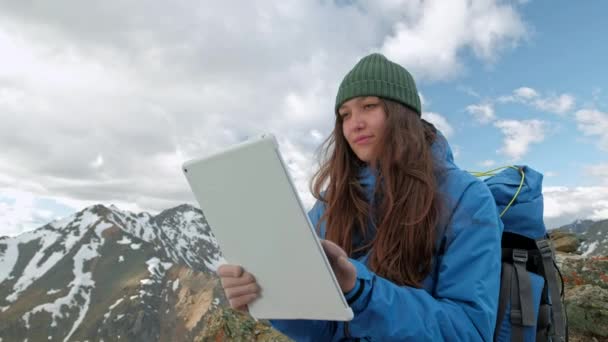 Πεζοπόρος κορίτσι με ένα tablet που κάθεται σε έναν βράχο με φόντο βουνά και τις λίμνες, Νορβηγία — Αρχείο Βίντεο