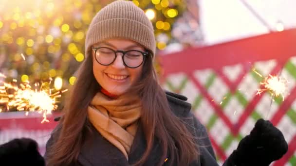 Ženy s jiskry v rukou, které bokeh města centra pozadí. Venku mladé krásné šťastné usmívající se dívka drží jiskru, chůze na ulici. — Stock video