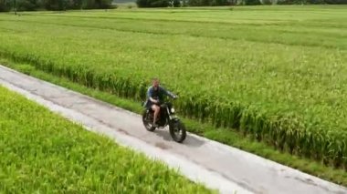 Motosiklet sürücüsü pirinç tarlalarına biniyor. Açık çekim, kırsal manzara. Seyahat ve spor fotoğrafçılığı. Hız ve özgürlük kavramı.