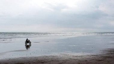 Sahilde motosiklet süren adam. Bali plaj günbatımı üzerinde vintage motosiklet. Genç hipster erkek özgürlük ve aktif yaşam tarzı zevk, bir bisikletçiler tur eğlenmek