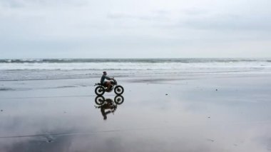 Sahilde motosiklet süren adam. Bali plaj günbatımı üzerinde vintage motosiklet. Genç hipster erkek özgürlük ve aktif yaşam tarzı zevk, bir bisikletçiler tur eğlenmek
