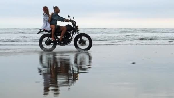 Unga vackra par hipsters rida retro motorcykel på stranden, utomhus porträtt, ridning kille och flicka, resa tillsammans, hav, hav — Stockvideo